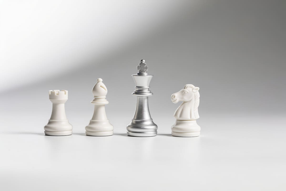 Three white ceramic chess pieces in a row, a king, a rook and a knight, on a light grey studio background