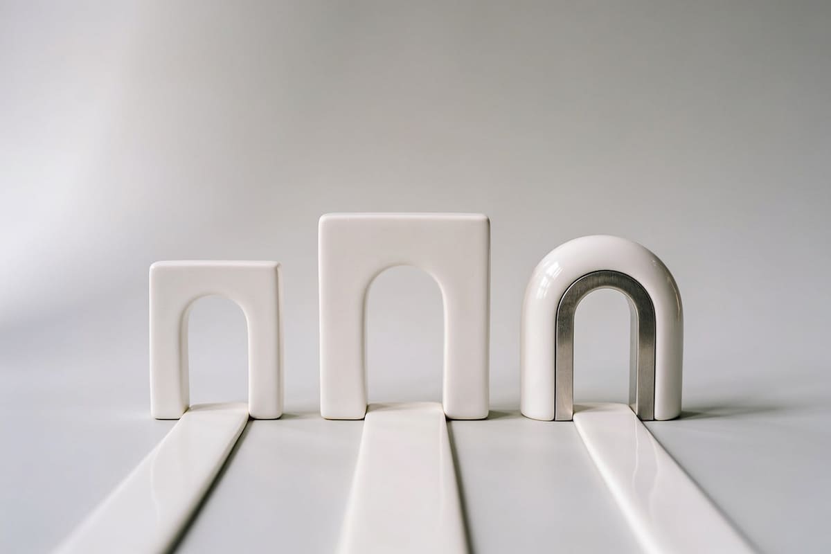 Three different white ceramic arches side by side, each with its own path, on a light grey studio background