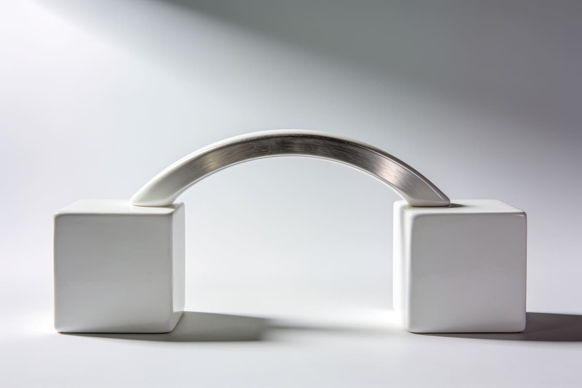 A white ceramic arch bridge spanning two blocks on a light grey studio background
